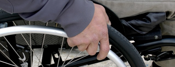 Nærbillede af en hånd på et kørestolshjul