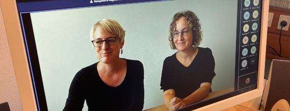 Foto af computerskærm med to smilende damer i sorte trøjer