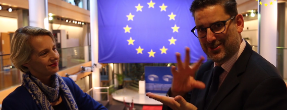 Helga Stevens og Adam Kosa i samtale på tegnsprog med EU-flaget i baggrunden