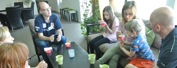 Fem voksne og to børn sidder om et bord med kaffekopper og soft-ice-bægre.