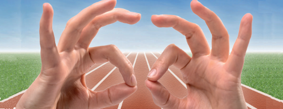 Nærbillede af to hænder med en løbebane i baggrunden, som viser tegnet for held og lykke
