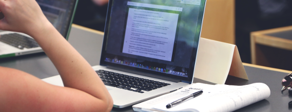 Billede af kursusdeltager set bagfra. Man ser kun hendes arm og hendes computerskærm på bordet foran hende.