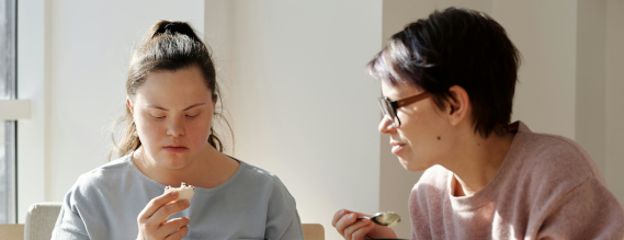 Ung kvinde med Down syndrom kigger skeptisk på noget, hun skal spise