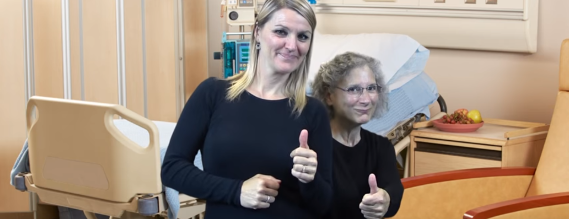 Billede fra videoen, som viser to kvindelige tolke på en hospitalsstue, som giver "thumbs up"