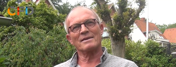 Stillbillede fra videoen der viser en moden mand, der står i sin have og taler til kameraet.