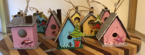 Fem fuglehuse i forskellige farver lavet i træ på en hylde