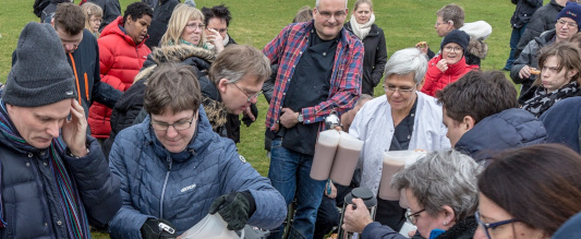 Gruppebillede af syv pædagoger og beboere for en gul rapsmark.