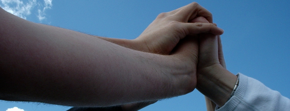 Fem hænder samlet i fælles håndtryk